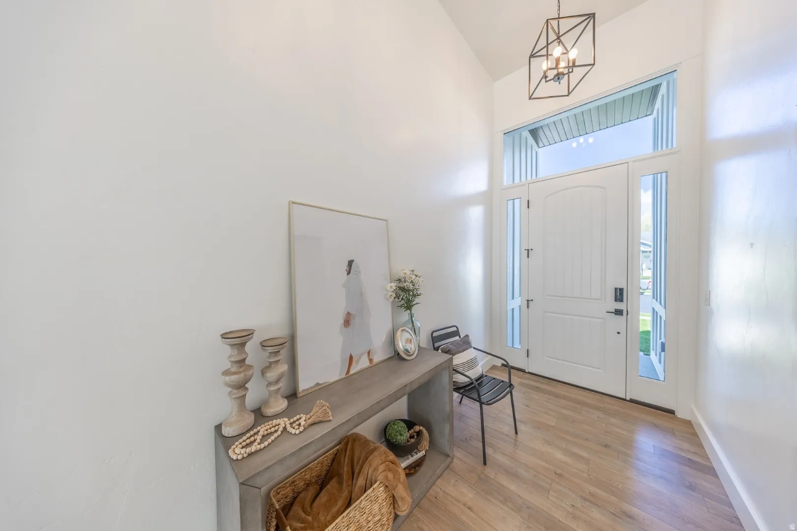 Foyer entrance featuring light wood-style floors, a chandelier, and lofted ceiling