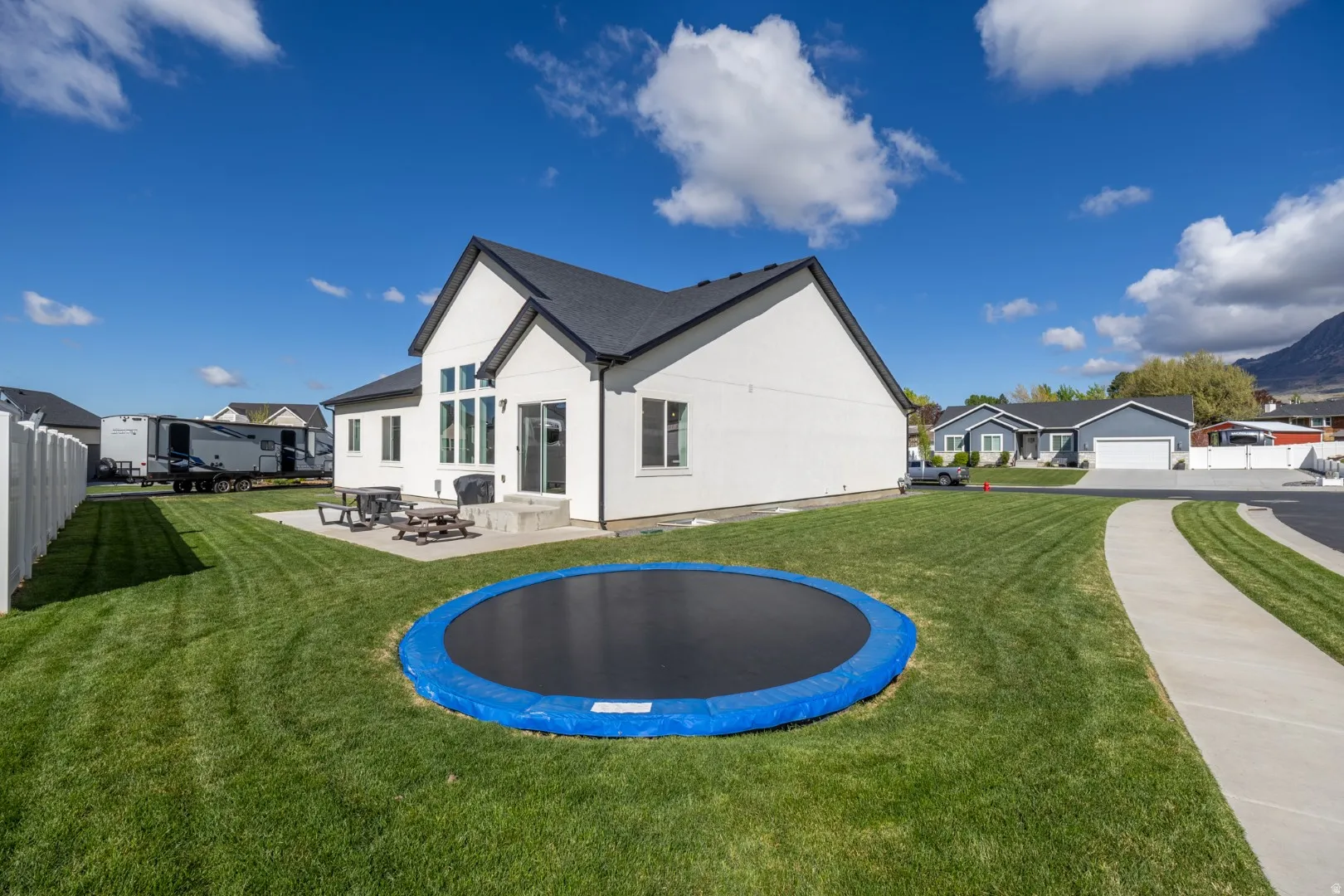 Back of property featuring a trampoline, a residential view, a patio area, and stucco siding