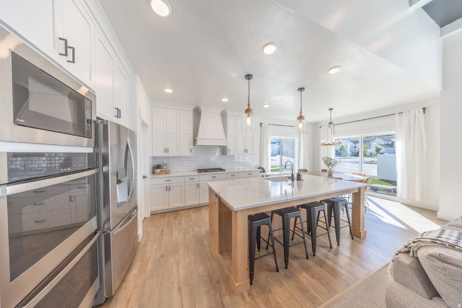 Kitchen with an island with sink, stainless steel appliances, light wood finished floors, a kitchen breakfast bar, and dual tone cabinets