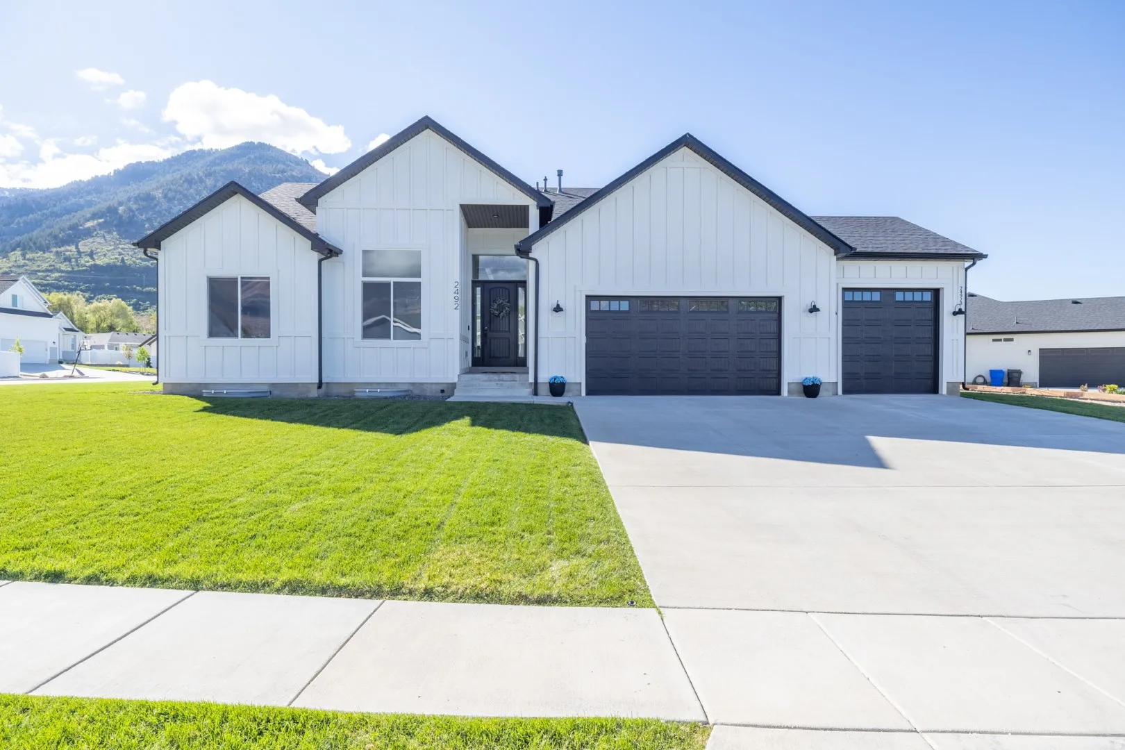 Modern farmhouse featuring board and batten siding, an attached garage, a mountain view, and concrete driveway