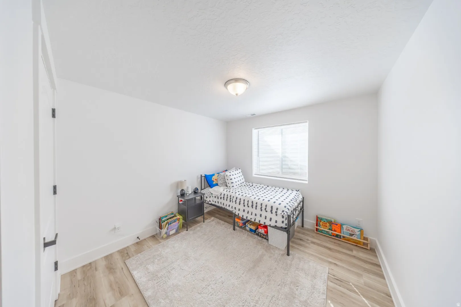 Bedroom with light wood-style flooring and a textured ceiling
