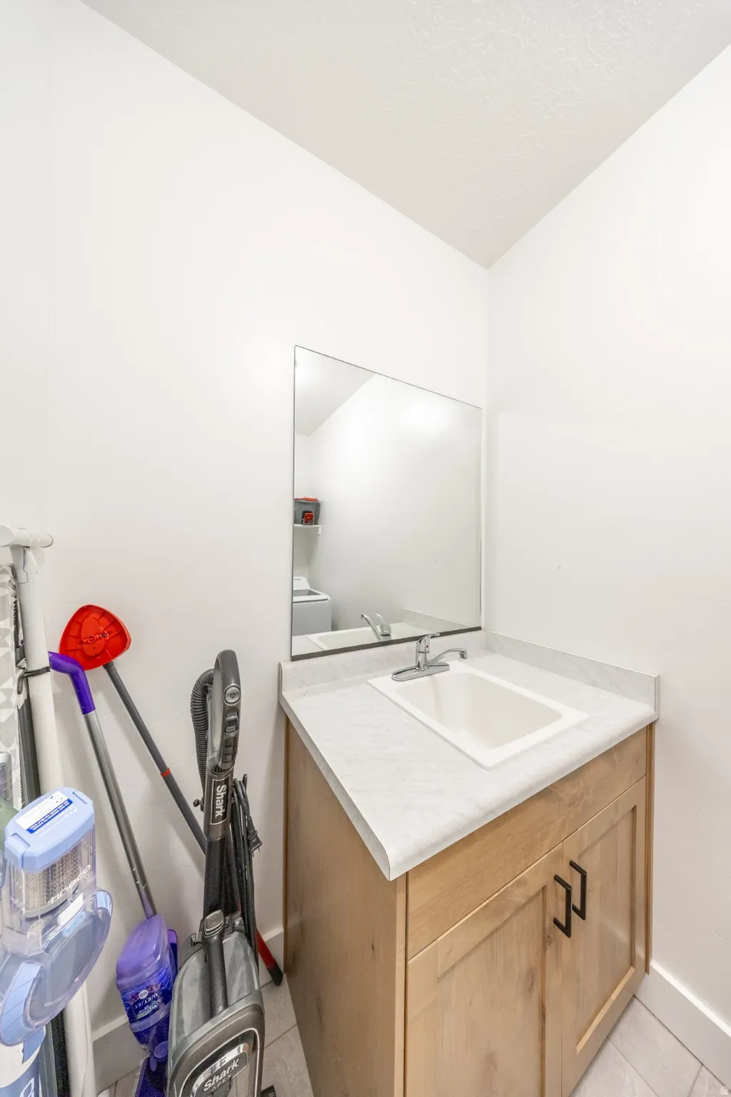 Half bath with vanity and light tile patterned flooring