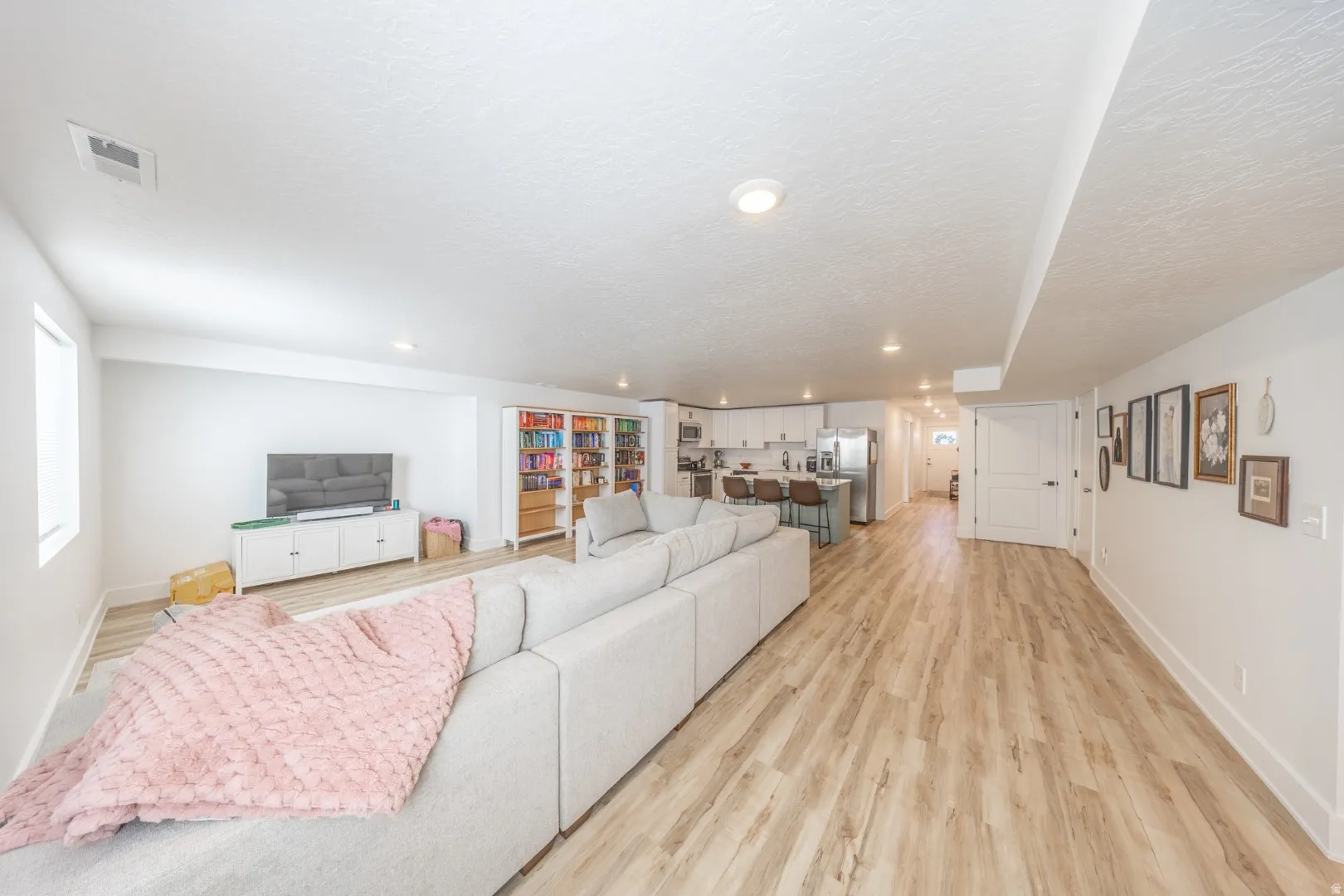 Living room featuring light wood-type flooring, a textured ceiling, and recessed lighting