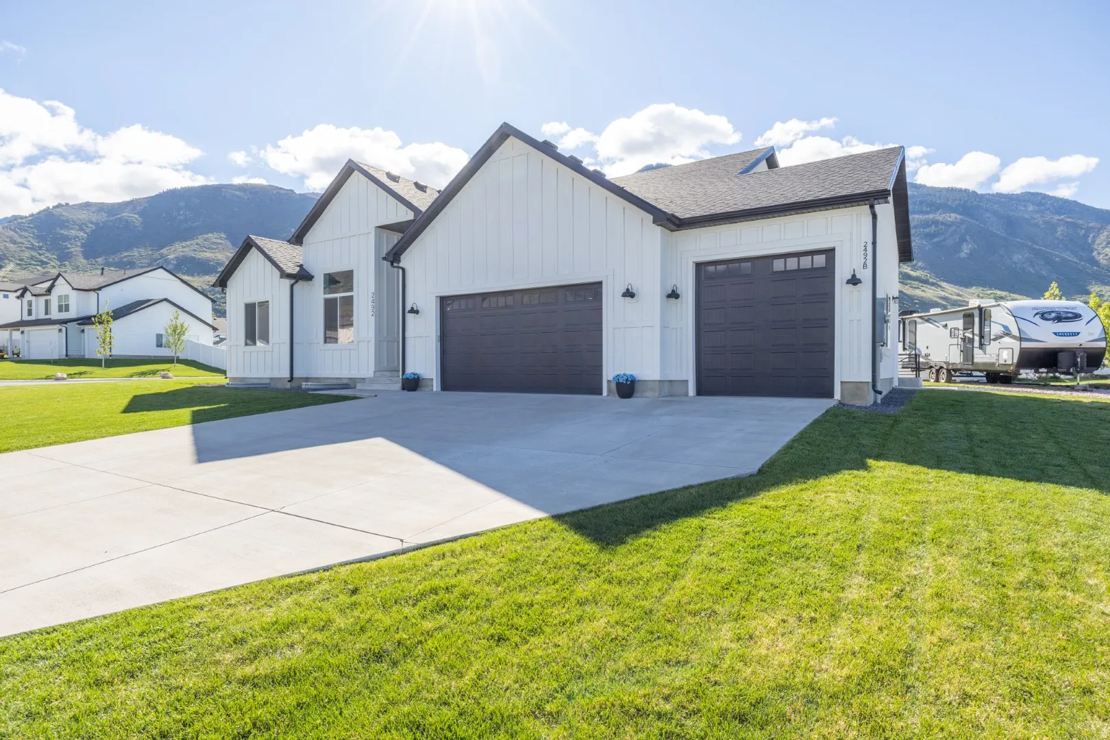 Modern inspired farmhouse featuring a mountain view, board and batten siding, an attached garage, and a front lawn