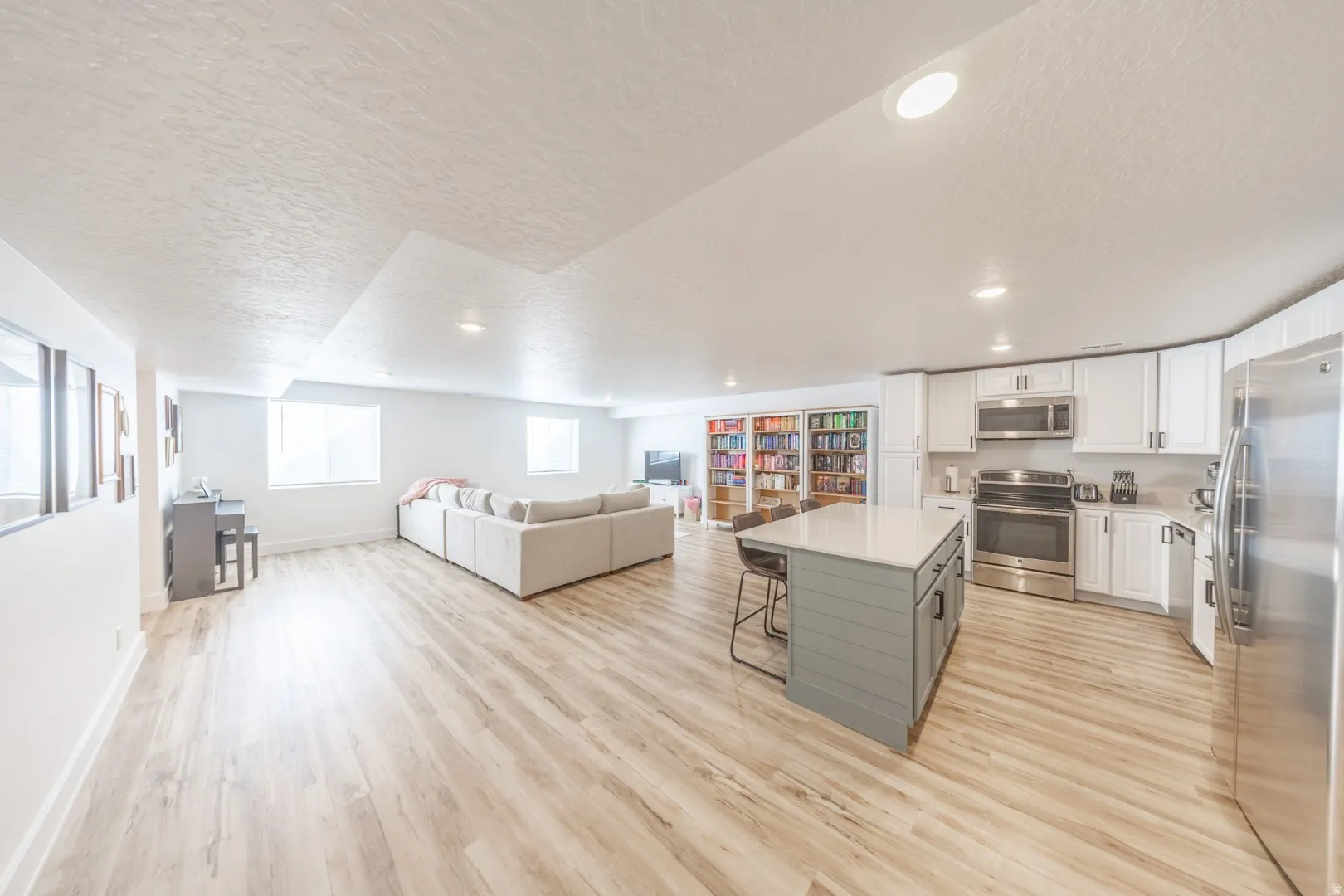 Dual tone kitchen featuring a kitchen breakfast bar, open floor plan, a textured ceiling, stainless steel appliances, and dual tone cabinetry