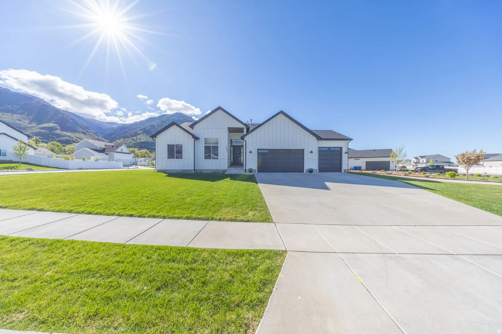 Modern farmhouse featuring a mountain view, board and batten siding, a front yard, and an attached garage