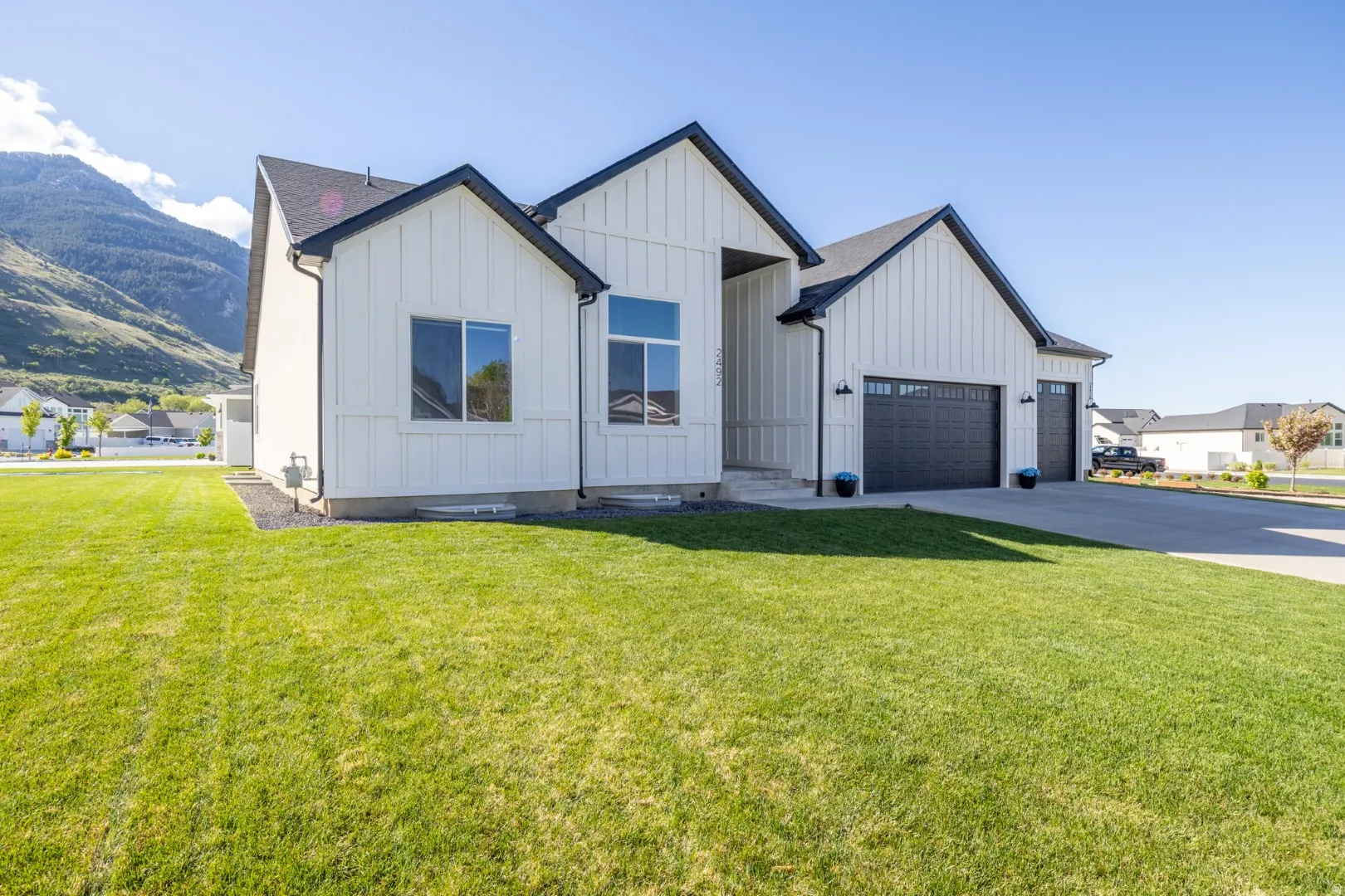 Modern farmhouse with board and batten siding, an attached garage, driveway, and a front yard