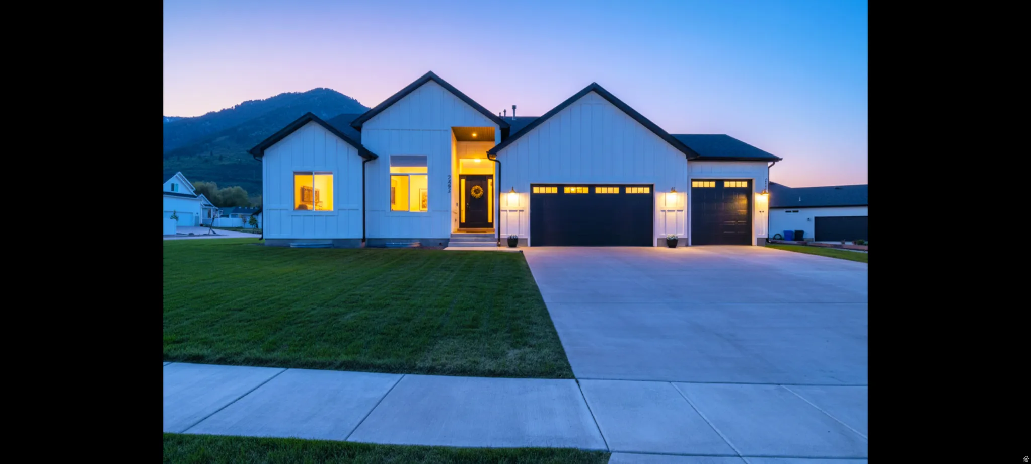 Modern farmhouse exterior featuring white board-and-batten siding, black-framed windows, and a black front door with a glass inlay