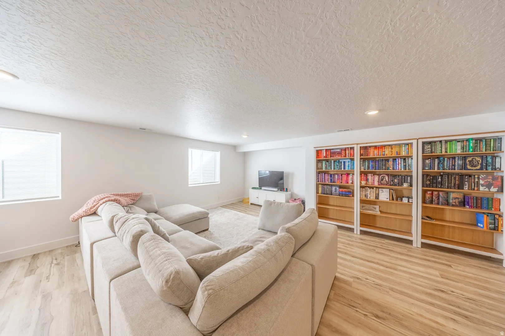 Living room with a textured ceiling, light wood-style floors, and recessed lighting
