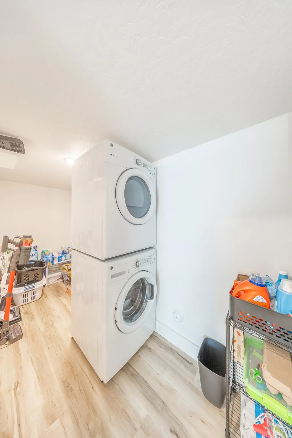 Laundry area with light wood-style floors and stacked washer and clothes dryer