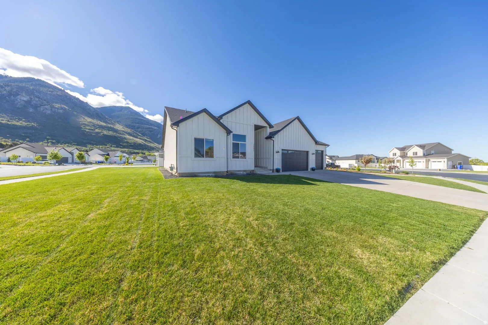 Modern inspired farmhouse featuring board and batten siding, a residential view, a mountain view, and a front yard