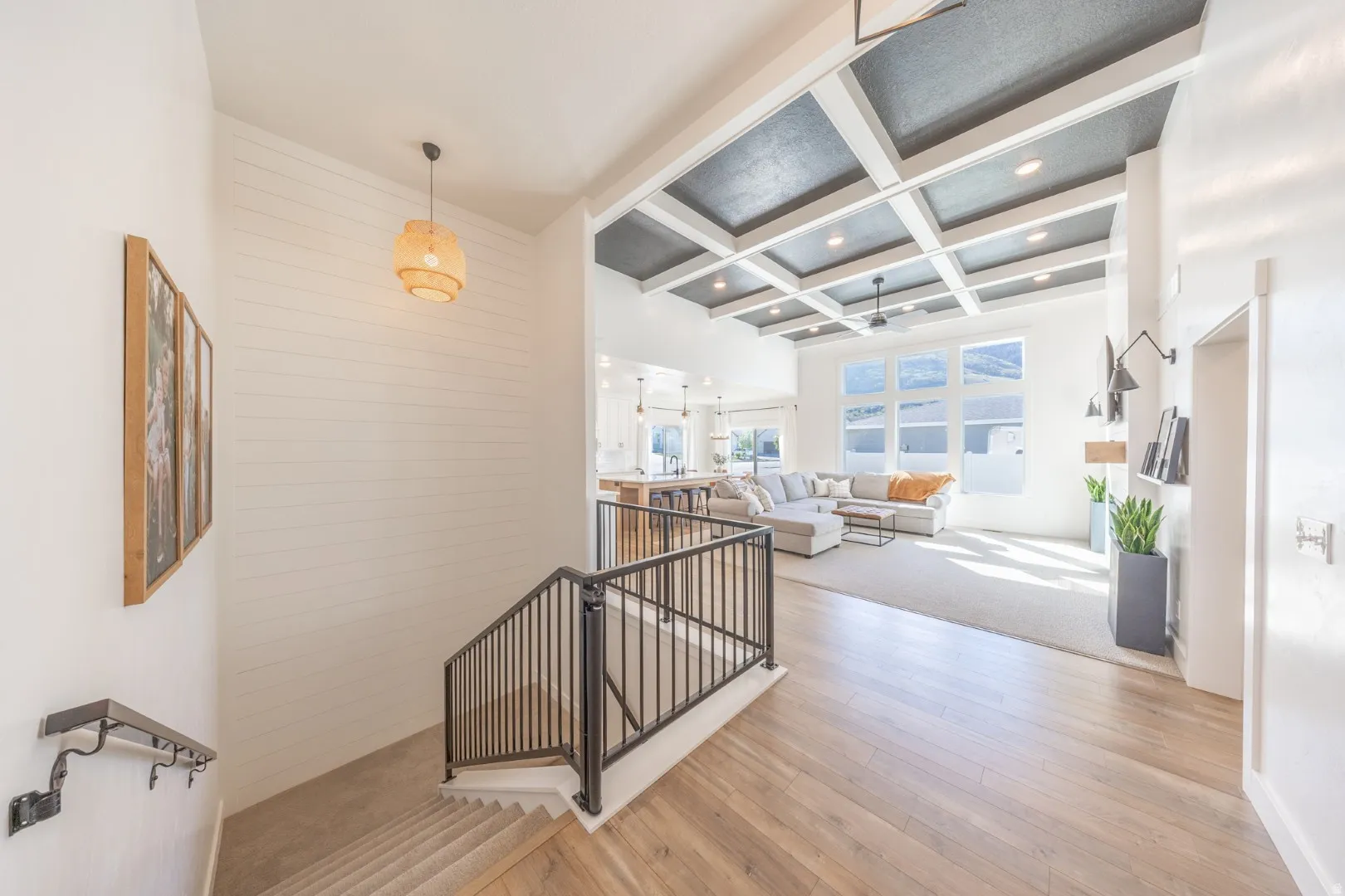 Hall with an upstairs landing, coffered ceiling, and light wood-style floors