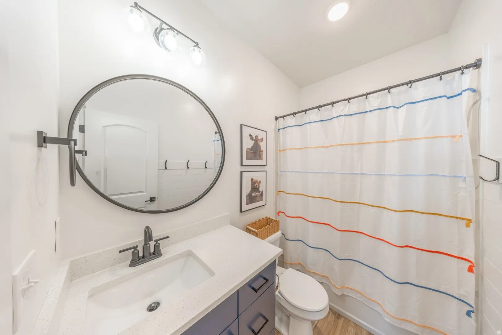 Full bath featuring vanity, shower / bathtub combination with curtain, and light wood-style floors