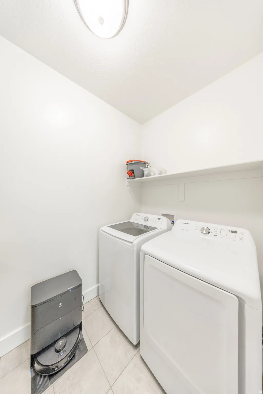 Laundry room with washing machine and clothes dryer and light tile patterned flooring