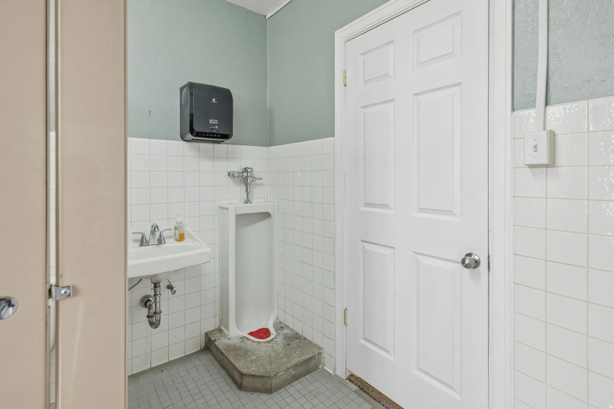 Bathroom with tile walls, a wainscoted wall, and light tile patterned floors