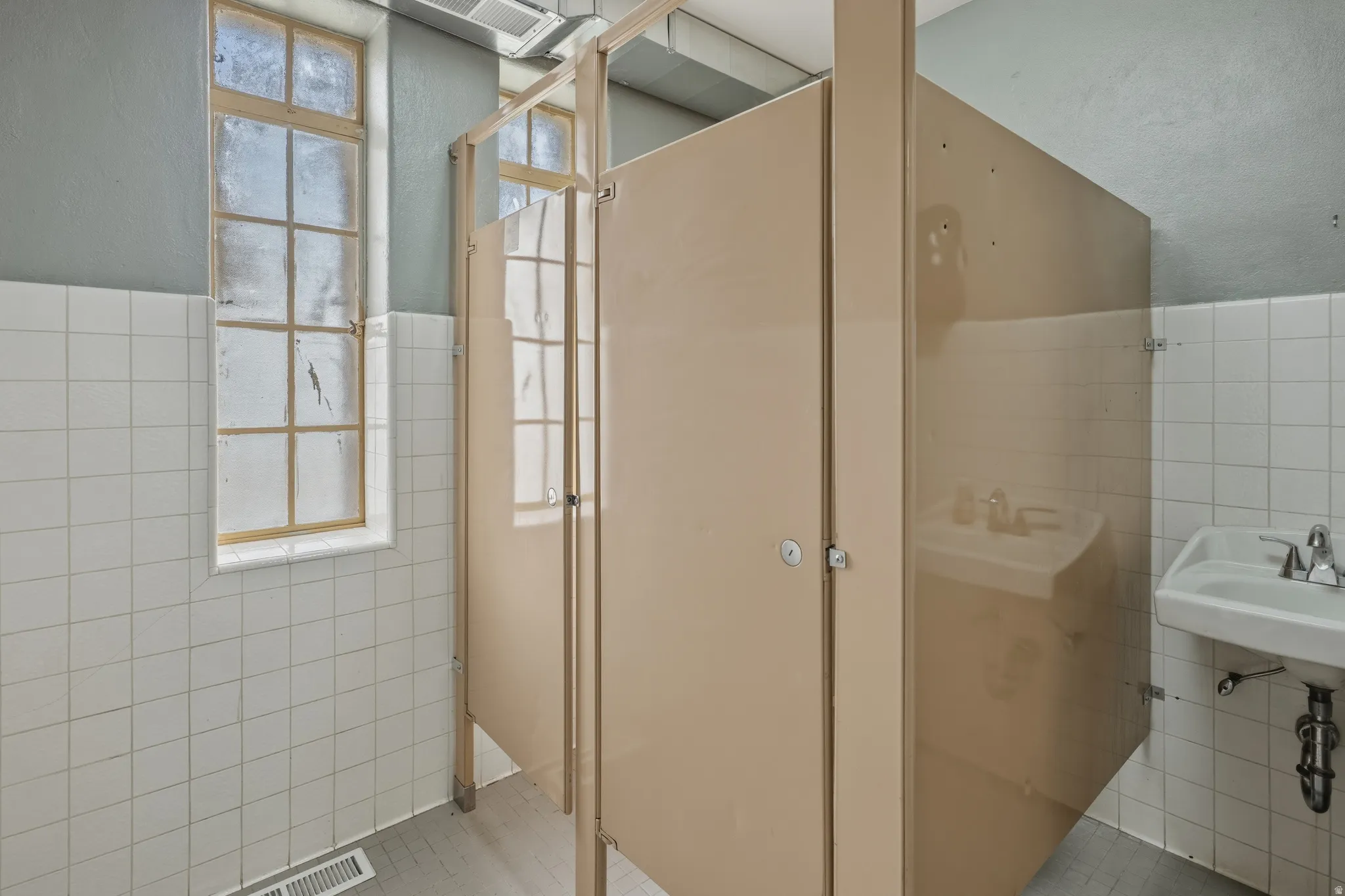 Bathroom with tile walls, a wainscoted wall, and a textured wall