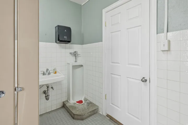 Bathroom with tile walls, a wainscoted wall, and light tile patterned floors