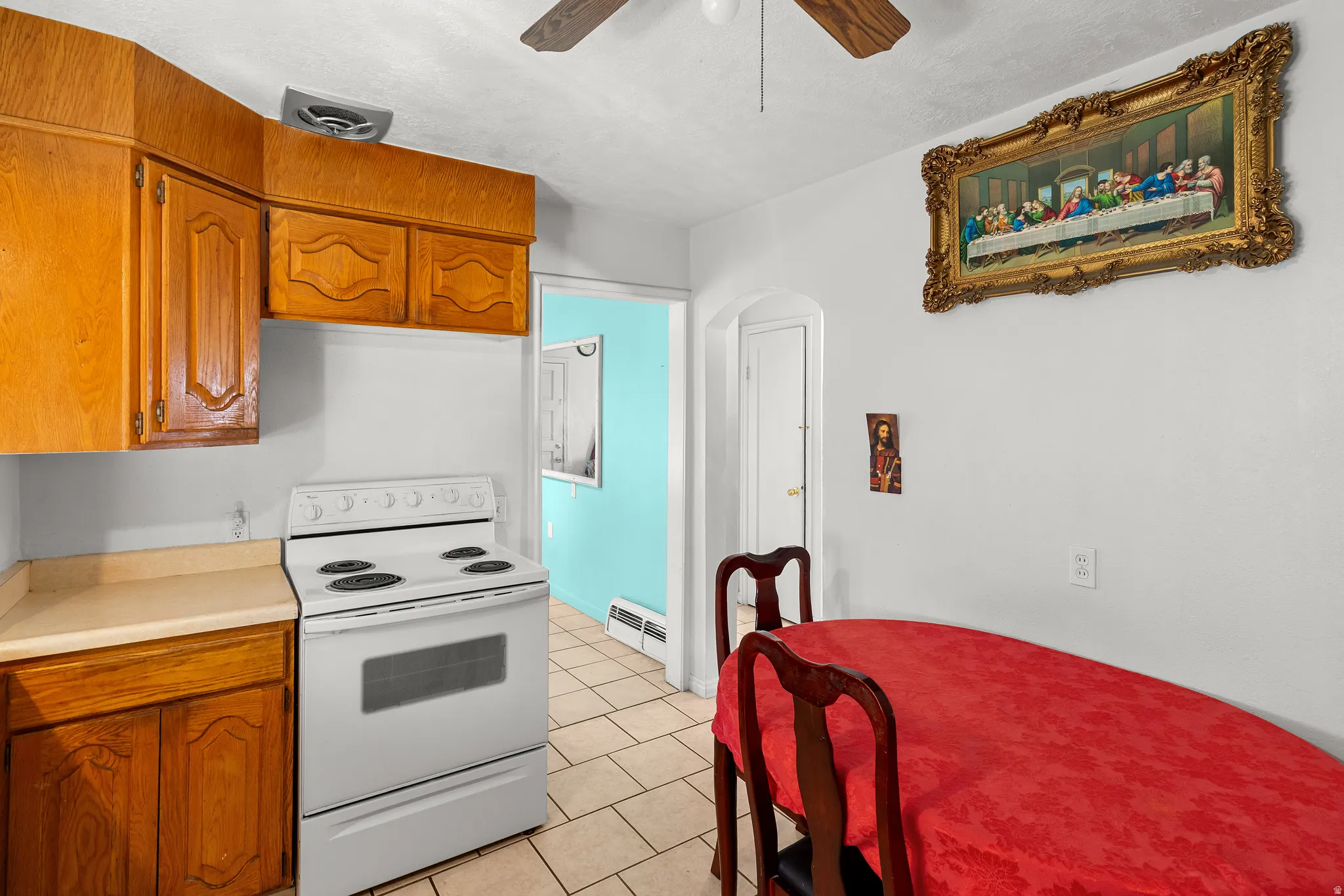 Kitchen featuring white range with electric stovetop, light countertops, arched walkways, wood finish cabinetry, and a ceiling fan