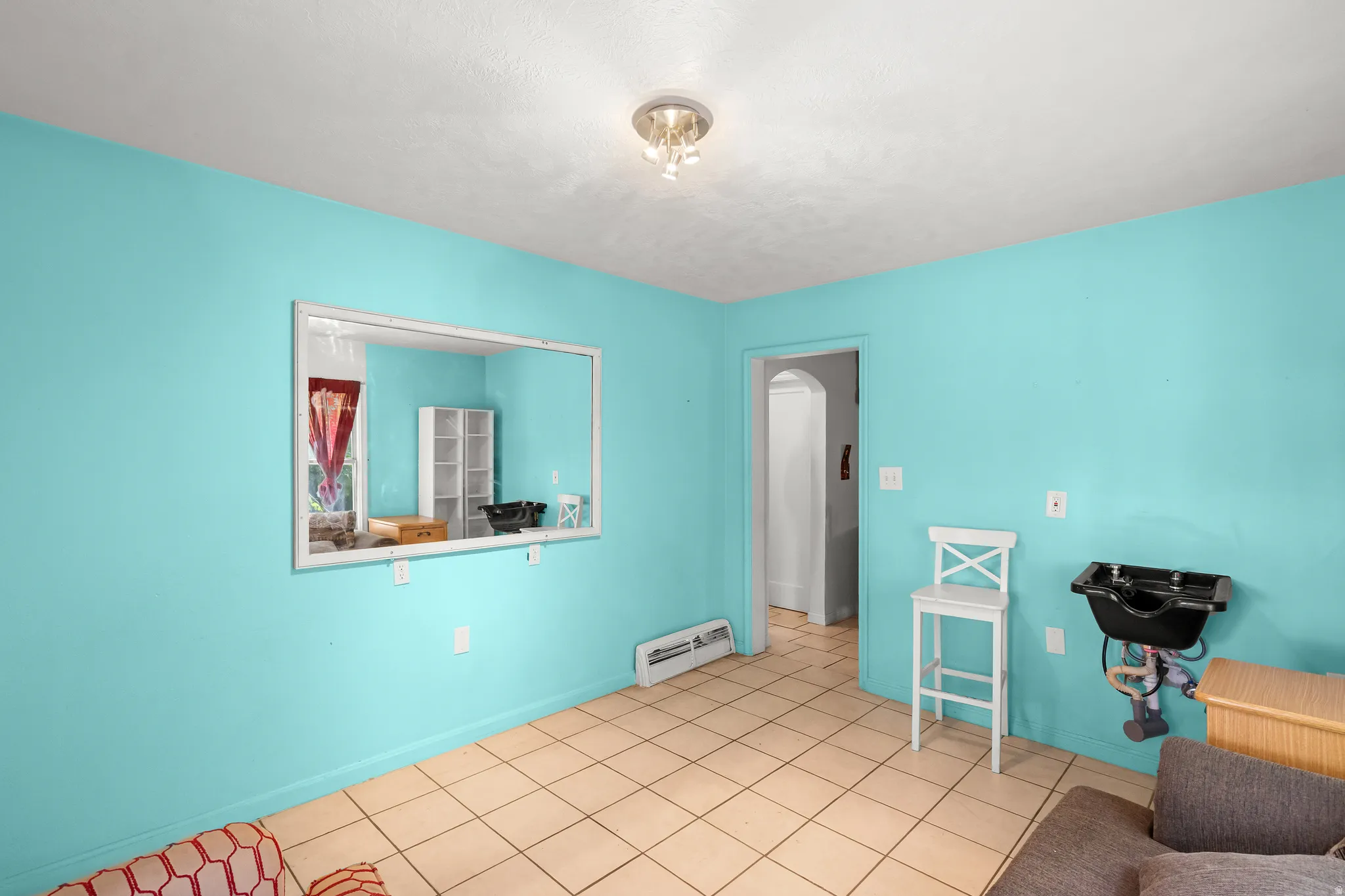 Living area featuring light tile patterned flooring, baseboard heating, and arched walkways