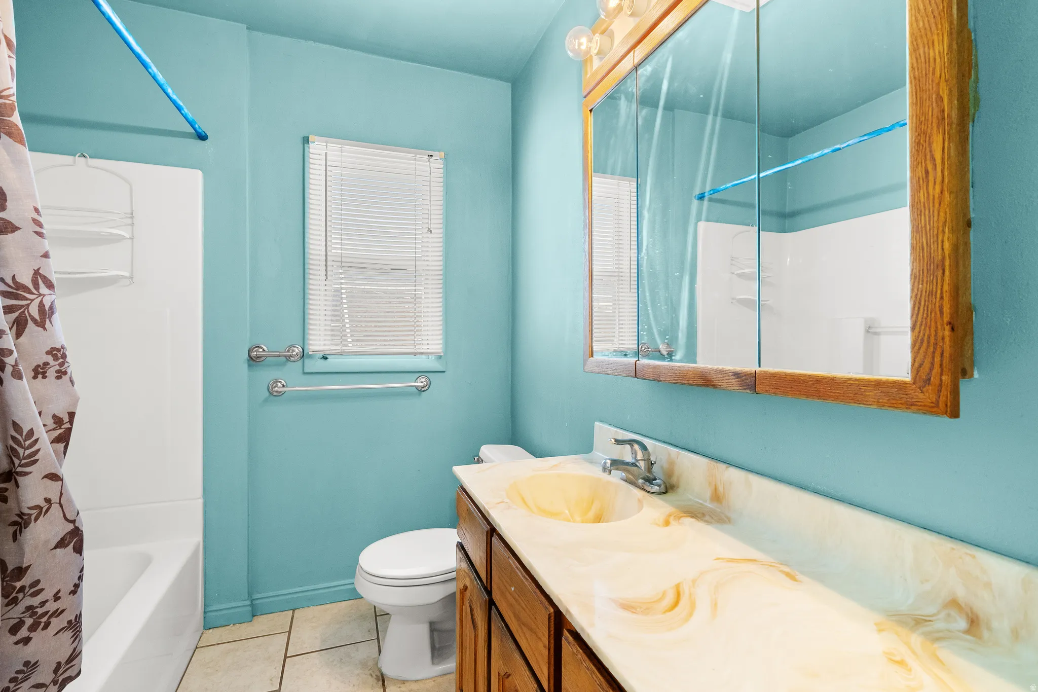 Bathroom featuring vanity, light tile patterned flooring, and shower / bath combo with shower curtain