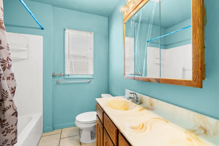 Bathroom featuring vanity, light tile patterned flooring, and shower / bath combo with shower curtain