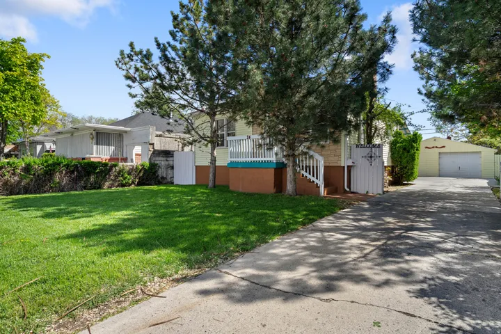 View of front facade featuring an outdoor structure, a garage, a front yard, and driveway