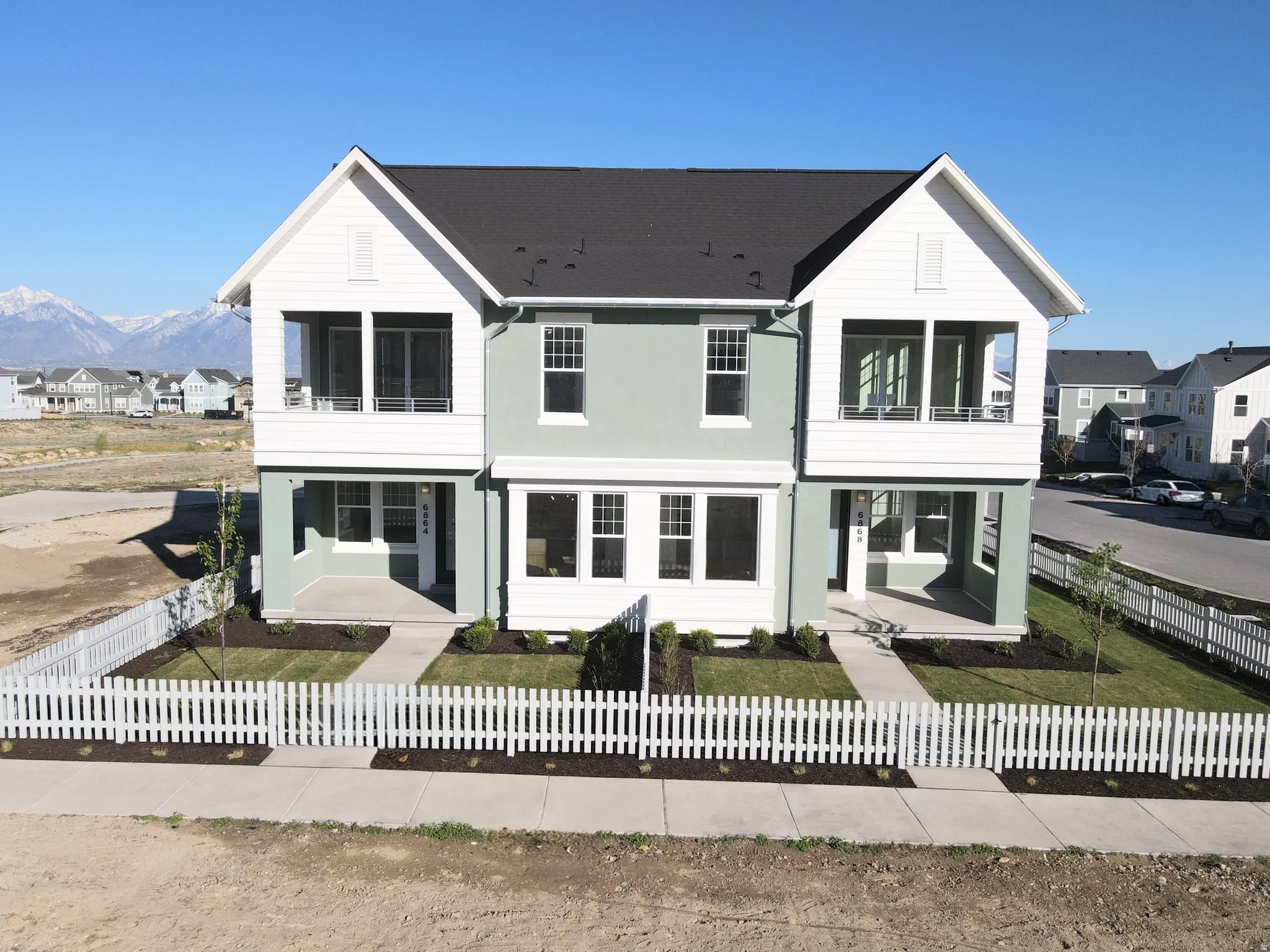 Exterior of home featuring a residential view, a balcony, a mountain view, and a fenced front yard