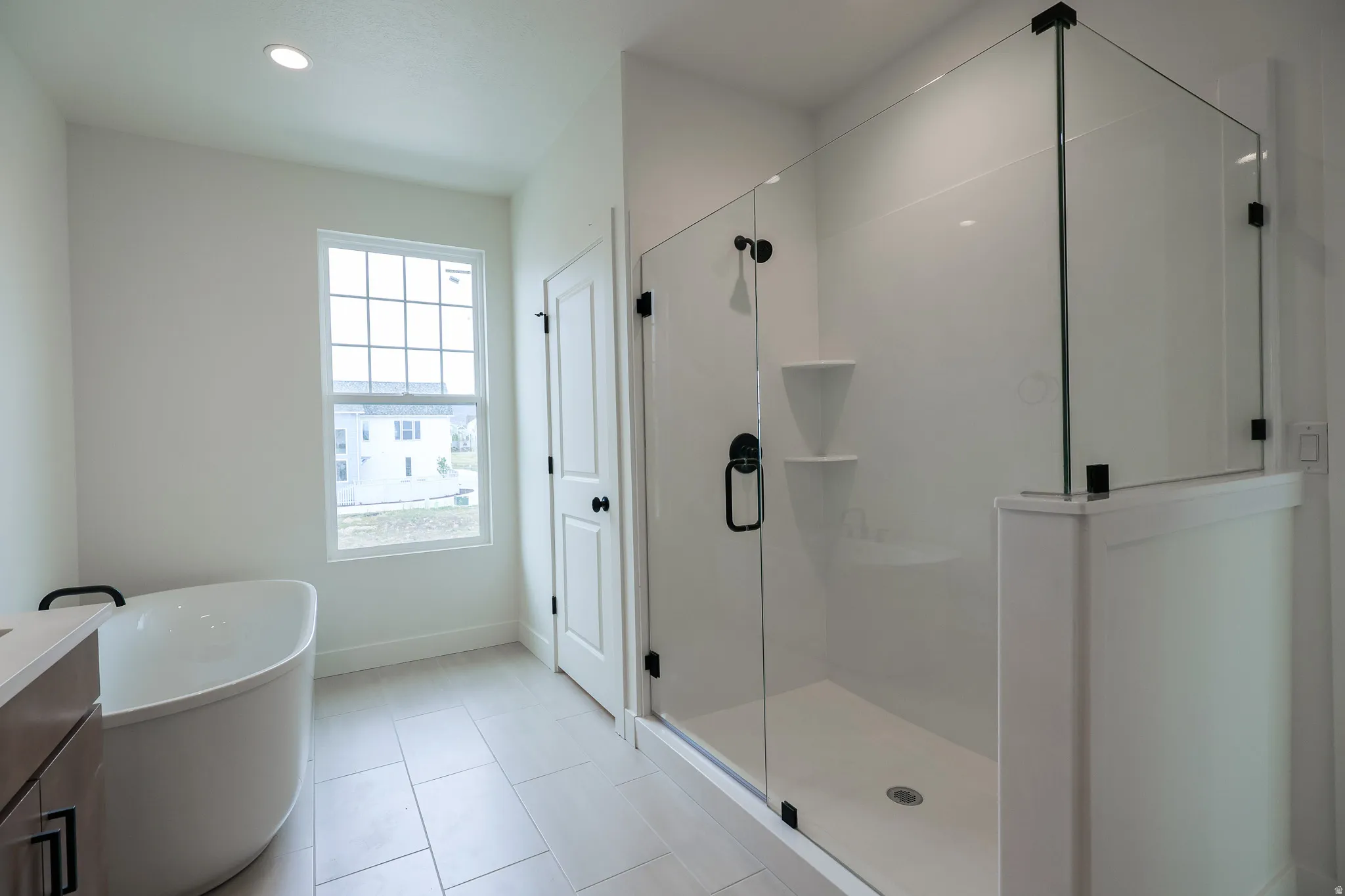 Primary Bathroom featuring a freestanding tub, a stall shower, vanity, recessed lighting, and light tile patterned floors