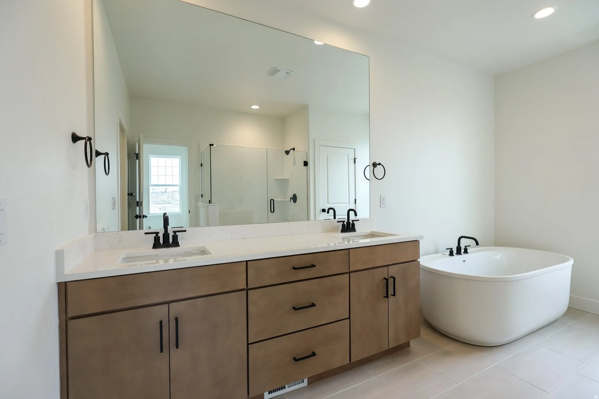 Primary Full bathroom featuring double vanity, a freestanding bath, a shower stall, recessed lighting, and light tile patterned floors