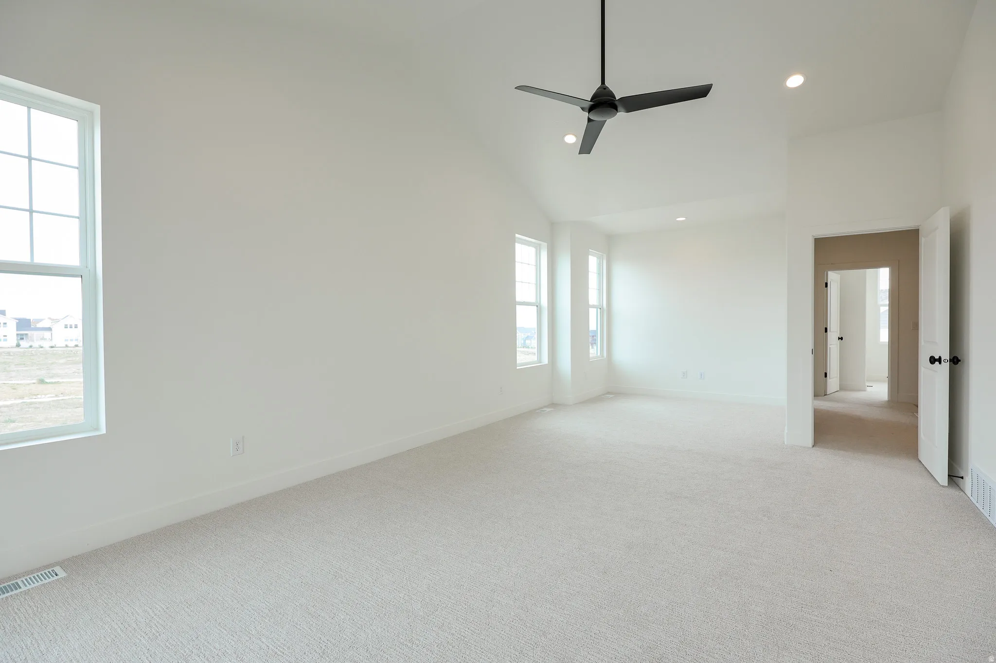 Primary bedroom with private balcony, ceiling fan, lofted ceiling, and recessed lighting