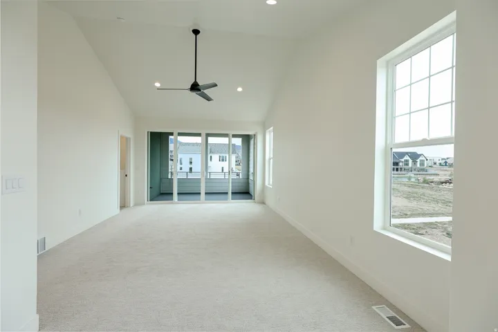 Primary bedroom with private balcony, ceiling fan, lofted ceiling, and recessed lighting