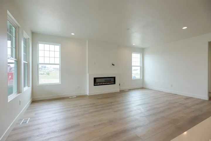 Unfurnished living room with light wood-style flooring, a glass covered fireplace, and recessed lighting