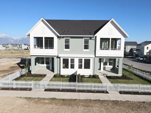 Exterior of home featuring a residential view, a balcony, a mountain view, and a fenced front yard