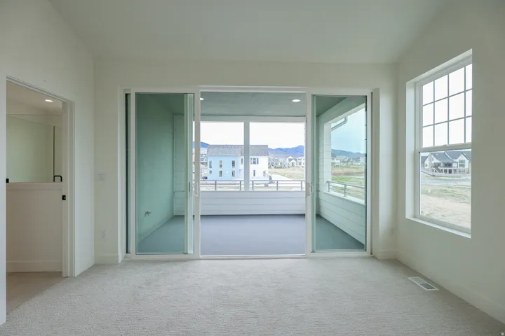 Primary bedroom with private balcony, ceiling fan, lofted ceiling, and recessed lighting