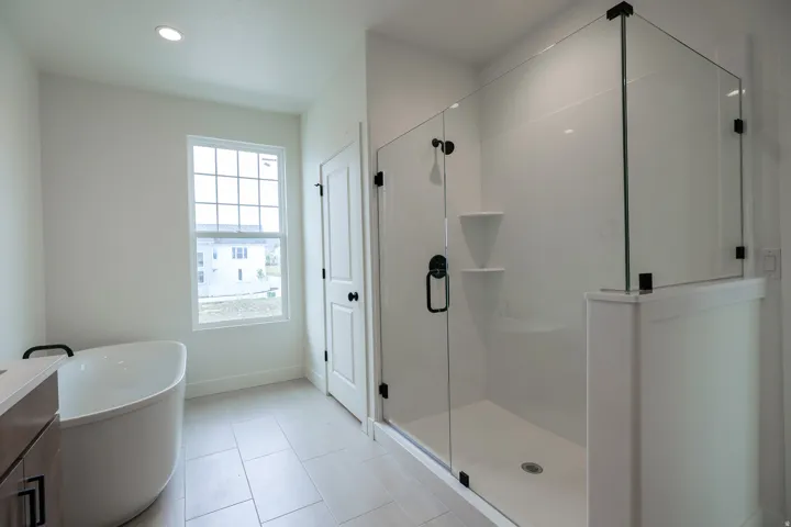 Primary Bathroom featuring a freestanding tub, a stall shower, vanity, recessed lighting, and light tile patterned floors