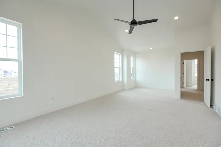 Primary bedroom with private balcony, ceiling fan, lofted ceiling, and recessed lighting