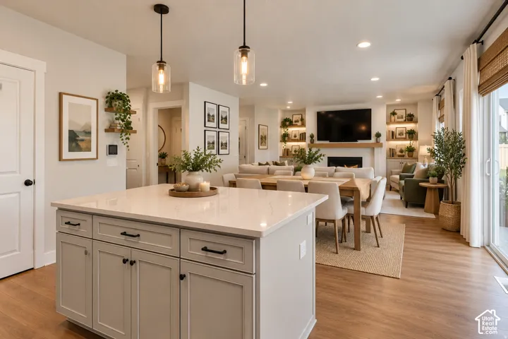 Spacious open-concept living area featuring wood-finish flooring, a kitchen island with stone countertop, recessed lighting, and sliding glass door
