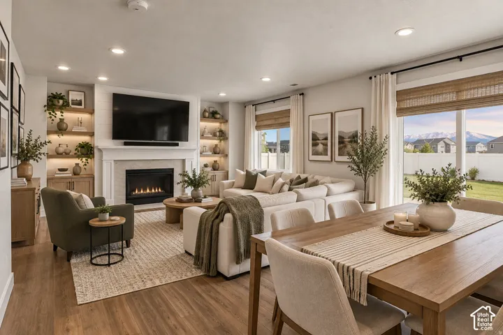 Open-concept living area featuring wood-finish flooring, recessed lighting, and a built-in fireplace with a mantel