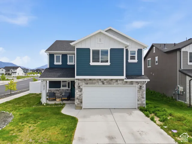 Craftsman-style home featuring stone siding, a front lawn, board and batten siding, a garage, and a residential view