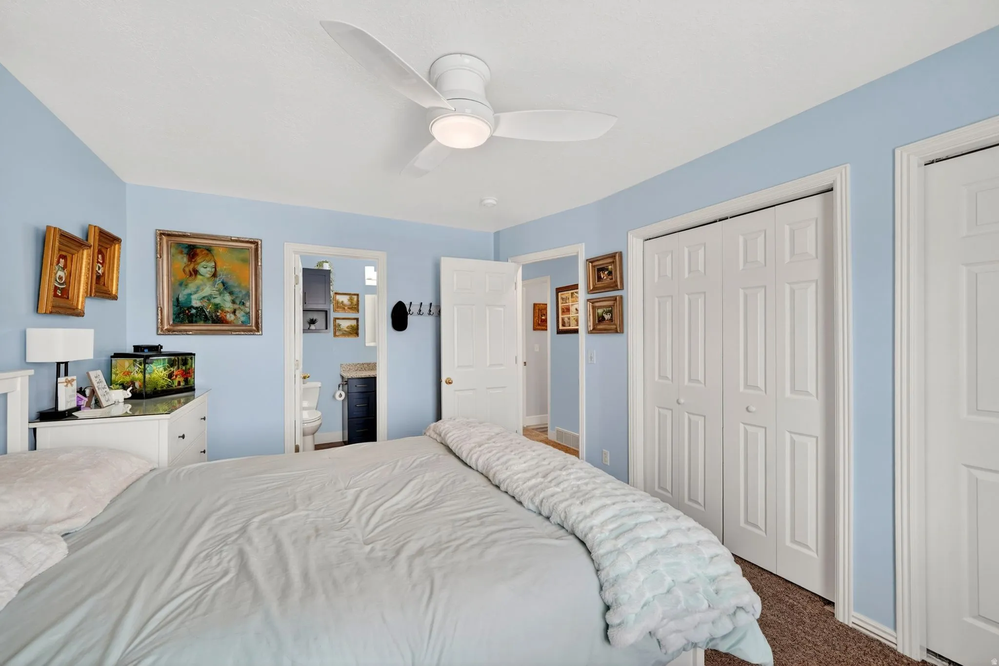 Bedroom featuring dark carpet, ceiling fan, and ensuite bath
