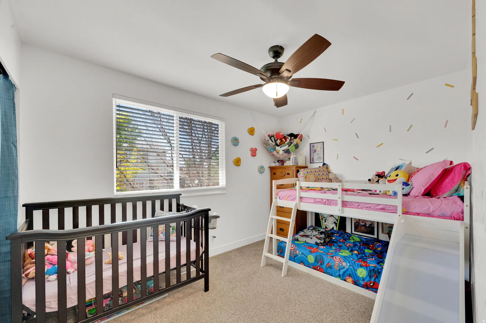 Bedroom with a nursery area, light carpet, and a ceiling fan