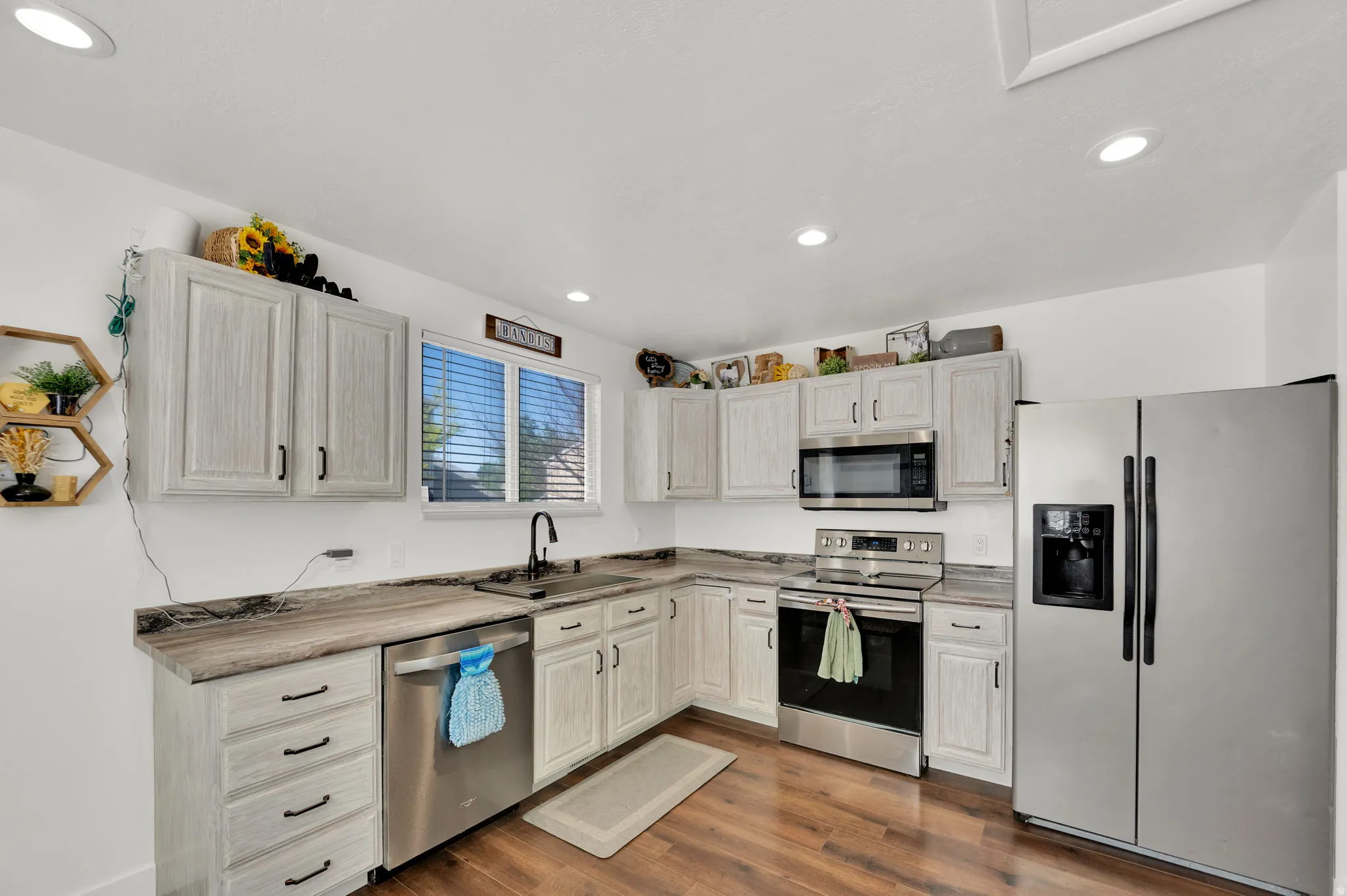 Kitchen with stainless steel appliances, light countertops, dark wood-style floors, and recessed lighting