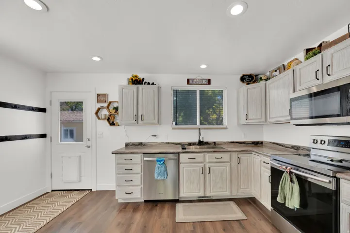 Kitchen featuring stainless steel appliances, dark wood-style floors, recessed lighting, and light countertops