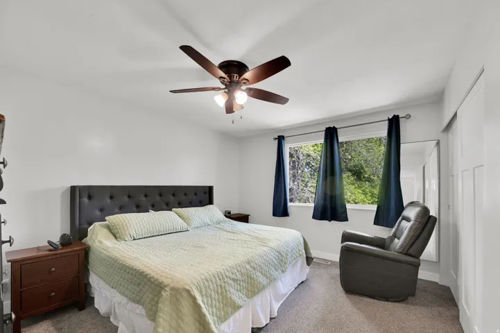 Carpeted bedroom with a closet and a ceiling fan