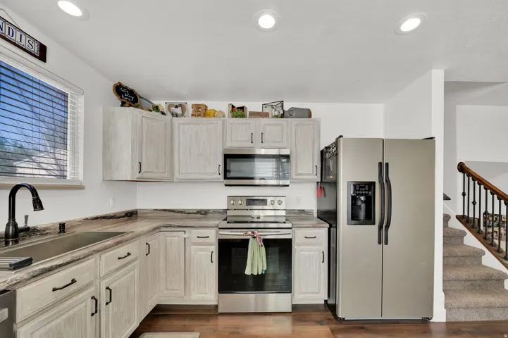Kitchen featuring stainless steel appliances, light countertops, dark wood-style flooring, and recessed lighting