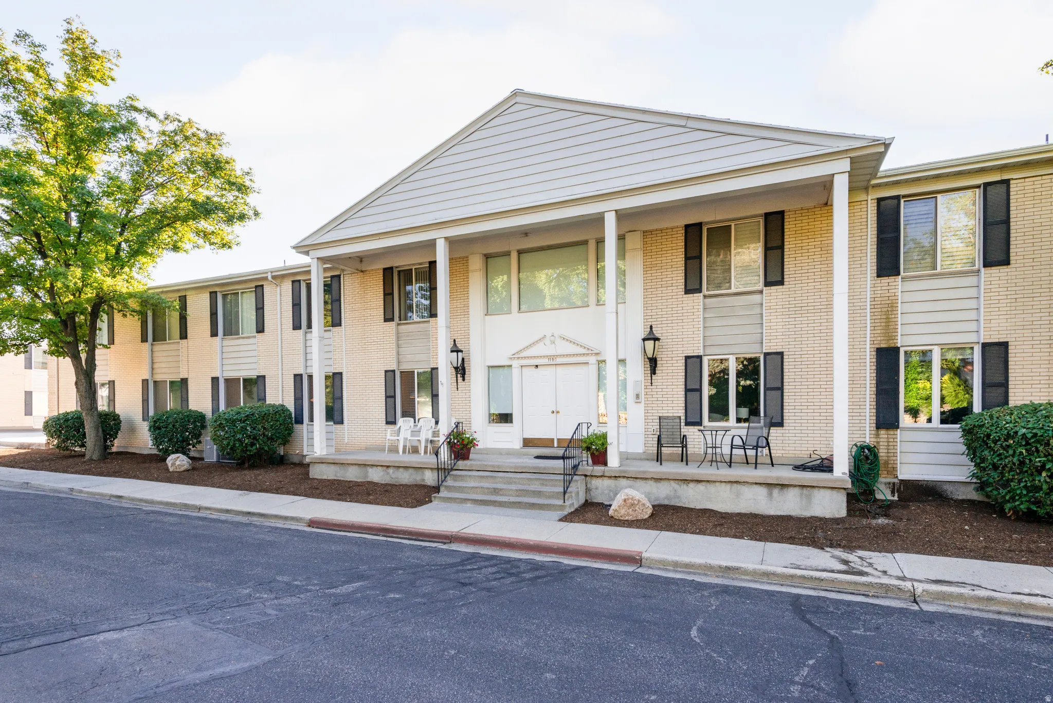Greek revival inspired property featuring a porch and brick siding