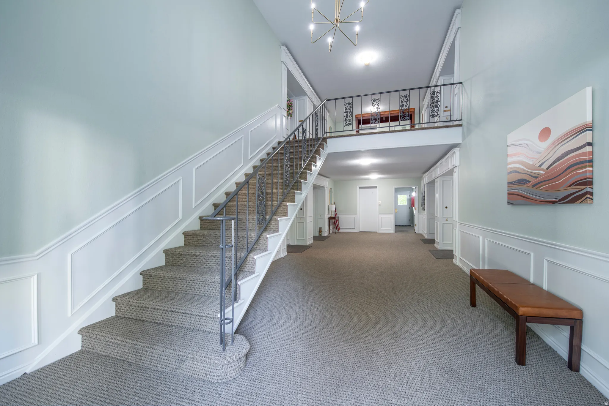 Stairway featuring a decorative wall, a chandelier, wainscoting, and carpet