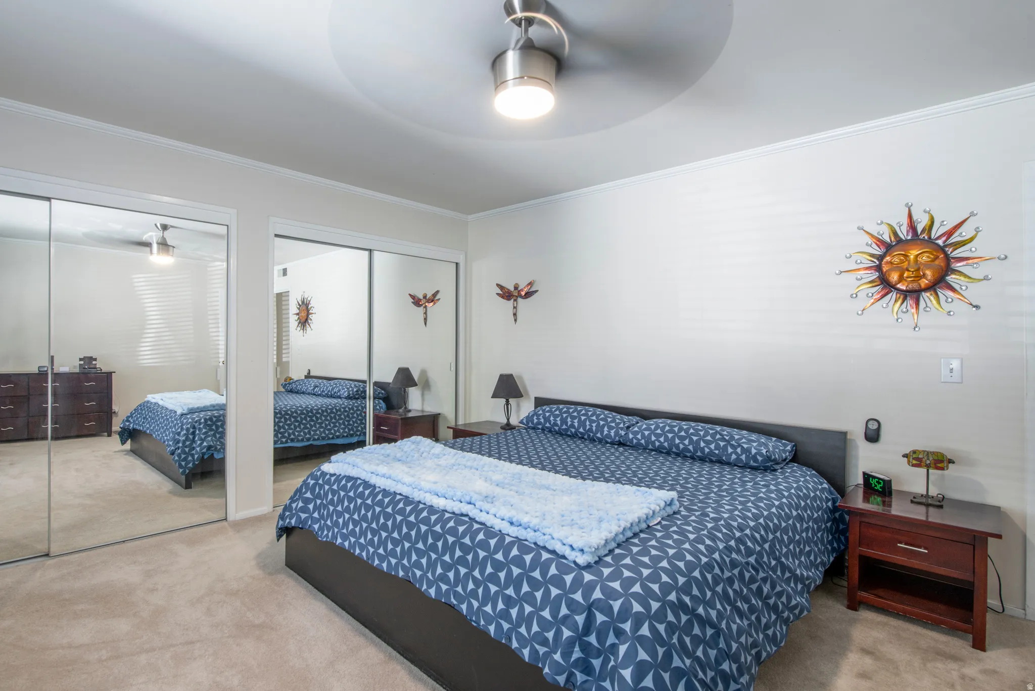 Bedroom with multiple closets, light carpet, crown molding, and a ceiling fan