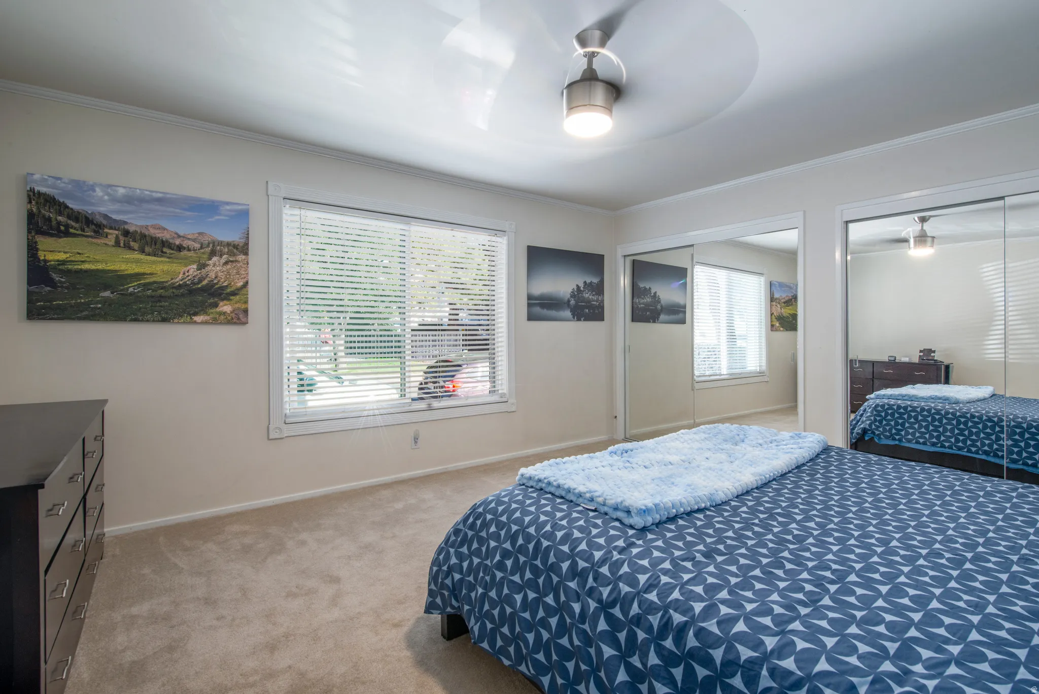 Bedroom featuring two closets, light colored carpet, ceiling fan, and ornamental molding