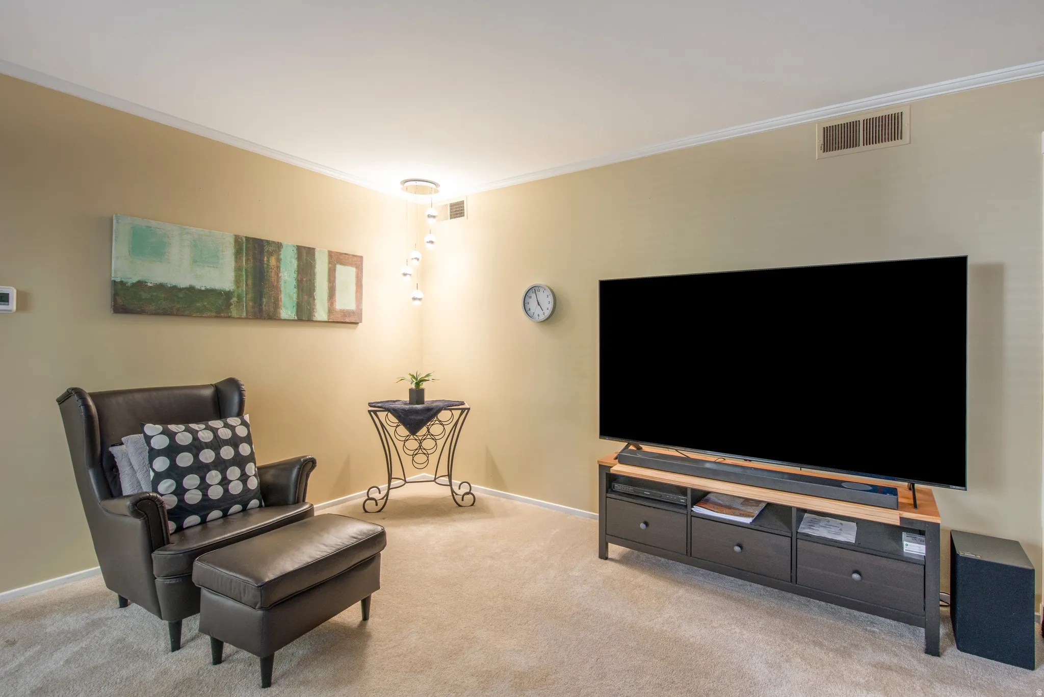 Living area with crown molding and light colored carpet